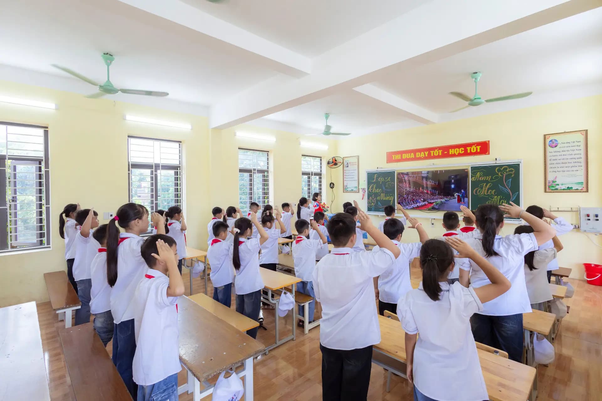 Students in a classroom raising their hands to answer a question
