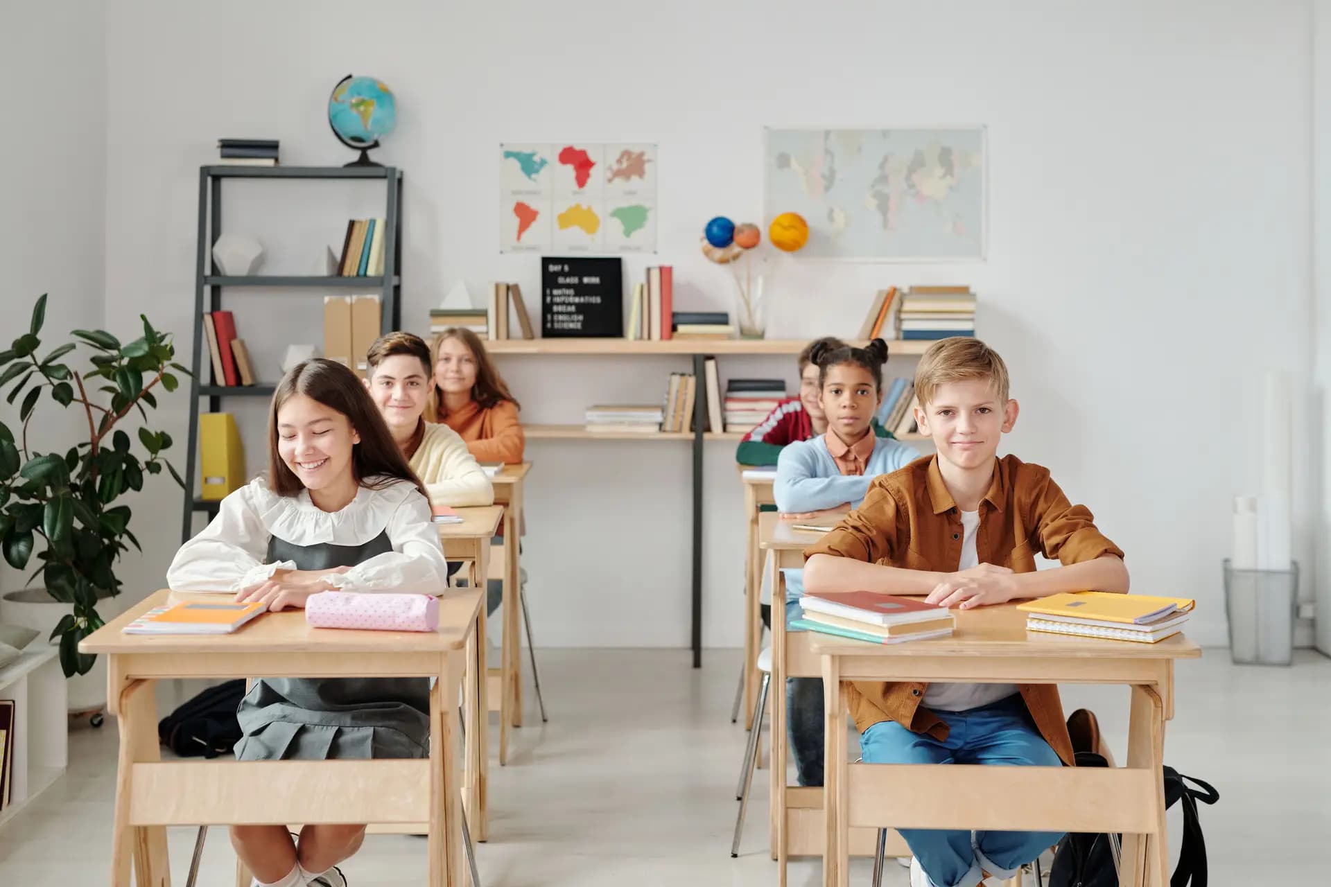 A teacher working with students at desks in a bright classroom