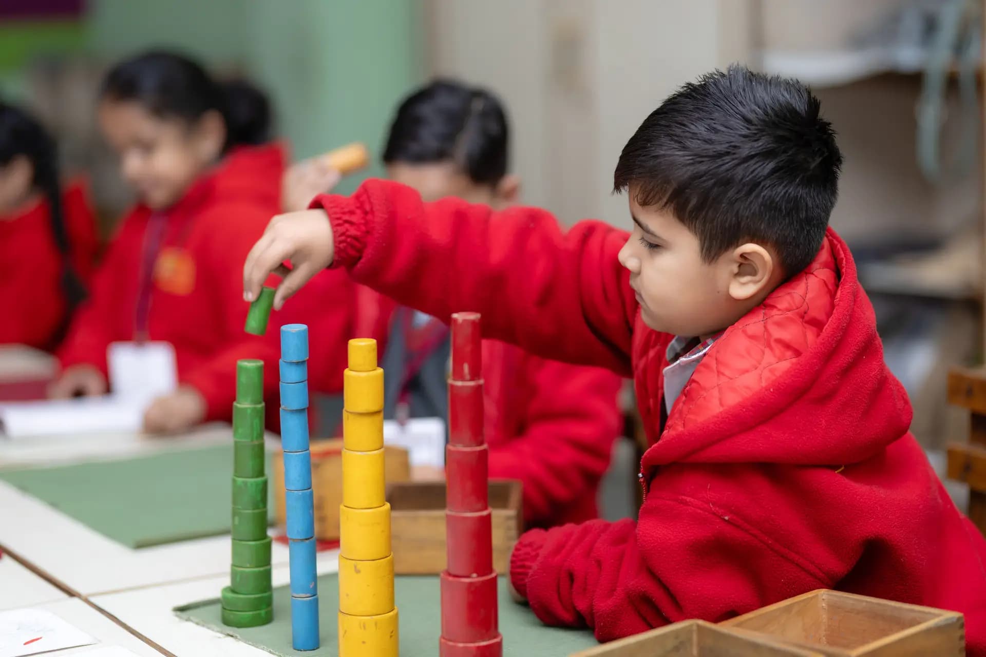A young student building a tower of coloured blocks in class